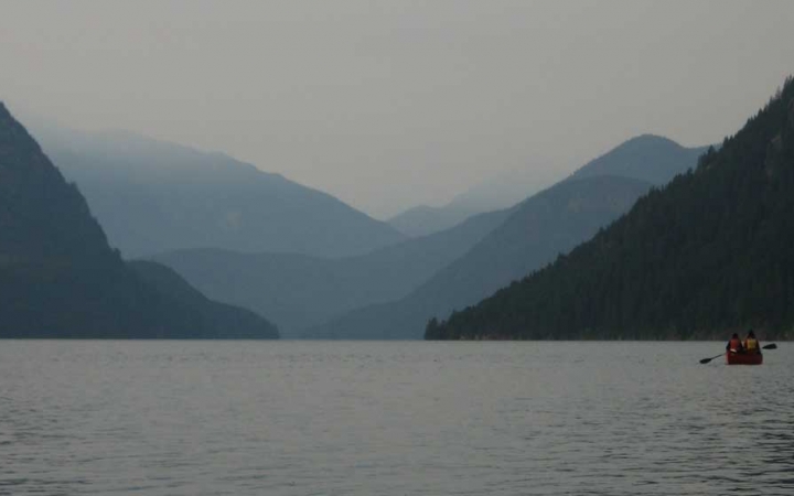 a canoe is paddled on a calm lake with blue mountains in the background